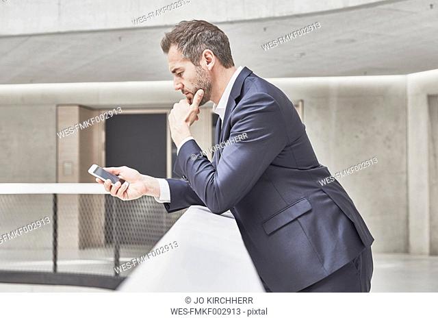 Businessman in office building looking at cell phone