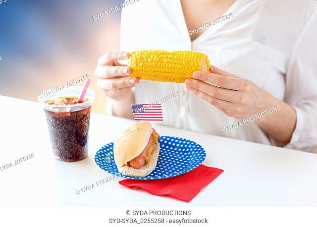woman eating corn with hot dog and cola