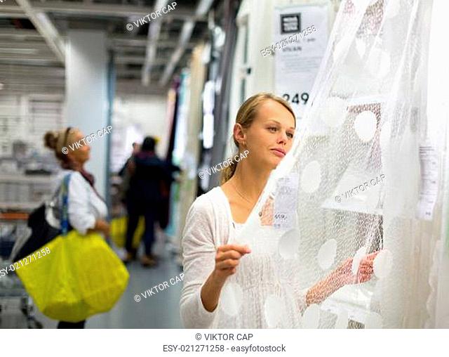 Pretty, young woman choosing the right curtains for her apartment in a modern home furnishings store