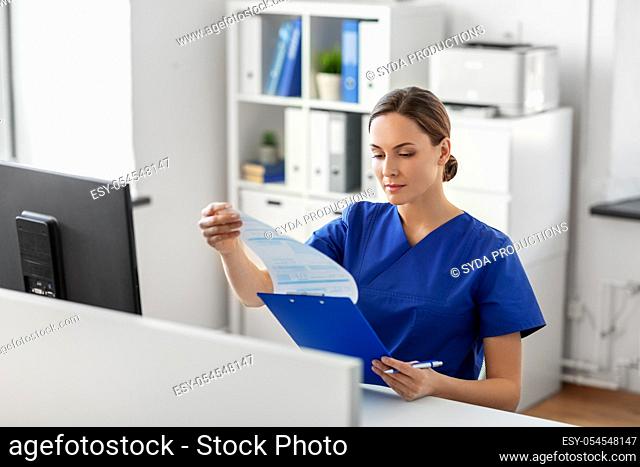 doctor or nurse with clipboard working at hospital