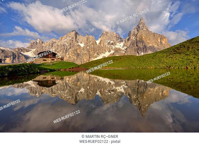 Italy, Trentino, Dolomites, Passo Rolle, Pale di San Martino range, Cimon della Pala with Baita Segantini reflecting in small lake in the evening