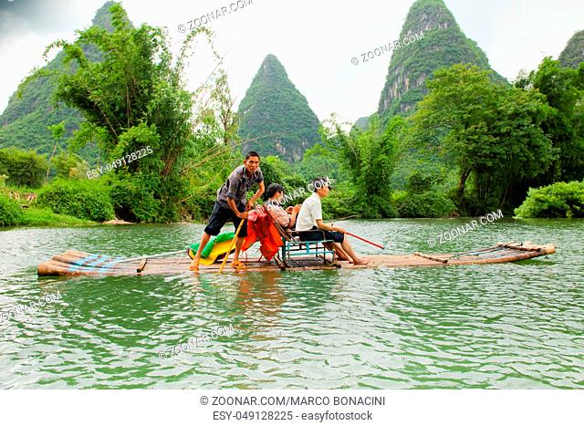 yulong river china July 2011: In July tourists travel on these bamboo rafts on the yulong river to admire the karst peaks covered with dense vegetation during...