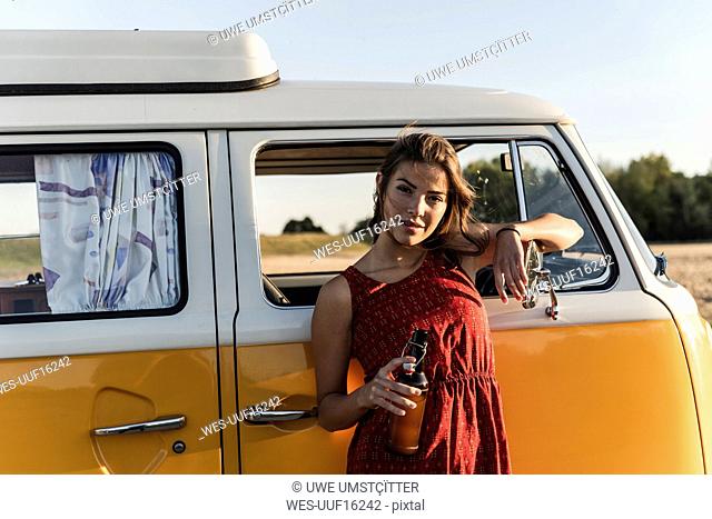 Pretty woman on a road trip with her camper, taking a break at sunset