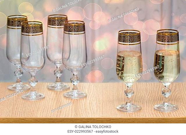 Six beautiful glass wine glasses, two filled with champagne