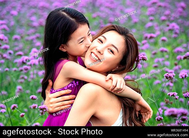 Happy mother and daughter playing in the flower sea