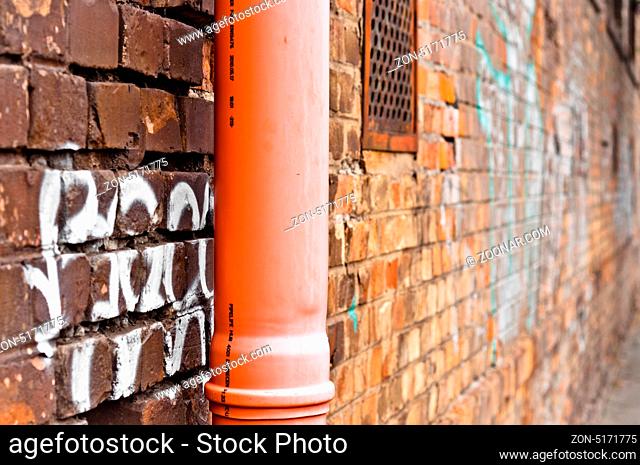 Sewage pipe on brick abandoned wall