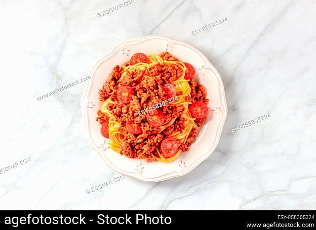 Spaghetti bolognese, overhead shot on a white marble background