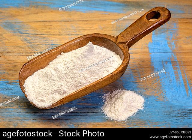 Cassava (yuca) flour on a rustic wooden scoop. It is a gluten free and grain free replacement for wheat flour
