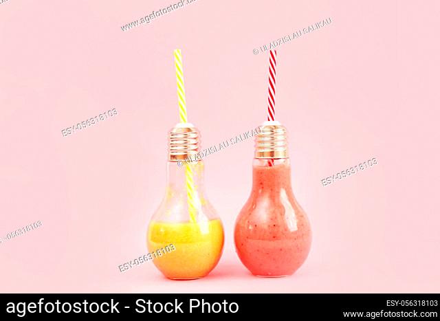 Two lamp- shaped jars with fruit smoothies isolated on pink background
