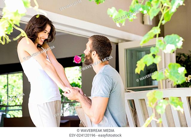 Young man proposing a woman with a flower