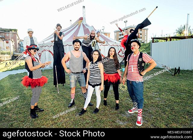 Happy circus performers standing on meadow