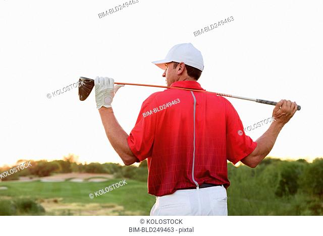 Hispanic golfer holding golf club on shoulders