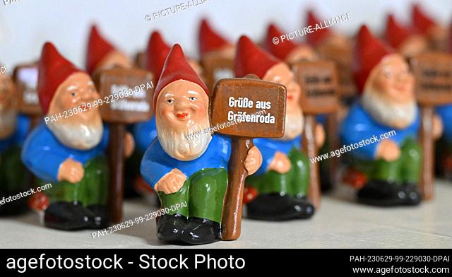 29 June 2023, Thuringia, Geratal: Signs reading ""Greetings from Gräfenroda"" are worn by garden gnomes in the store of Zwergstatt-Manufaktur Gräfenroda