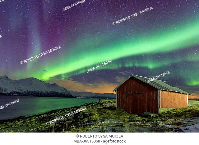 Northern Lights illuminates the wooden cabin at Svensby Lyngen Alps Tromsø Lapland Norway Europe