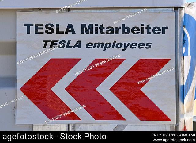 30 May 2021, Brandenburg, Grünheide: A signpost for employees at the Tesla Gigafactory construction site east of Berlin hangs from a tent