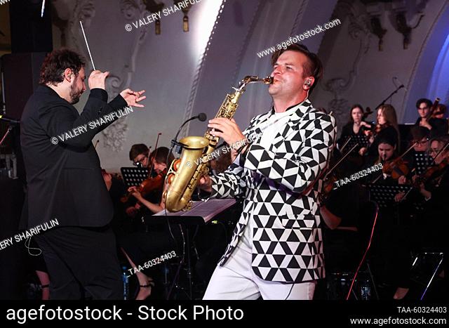 RUSSIA, MOSCOW - JULY 8, 2023: Conductor Artemy Menshchikov, saxophonist Taras Gusarov (L-R), and musicians of the Imperialis Orchestra perform during a concert...
