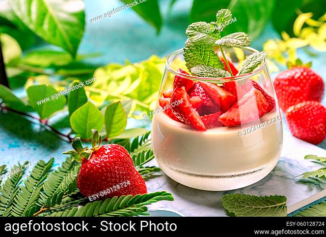 Matcha green tea panna cotta with coconut cream and strawberry slices in a glass. Concept of a healthy vegetarian gluten-free dessert