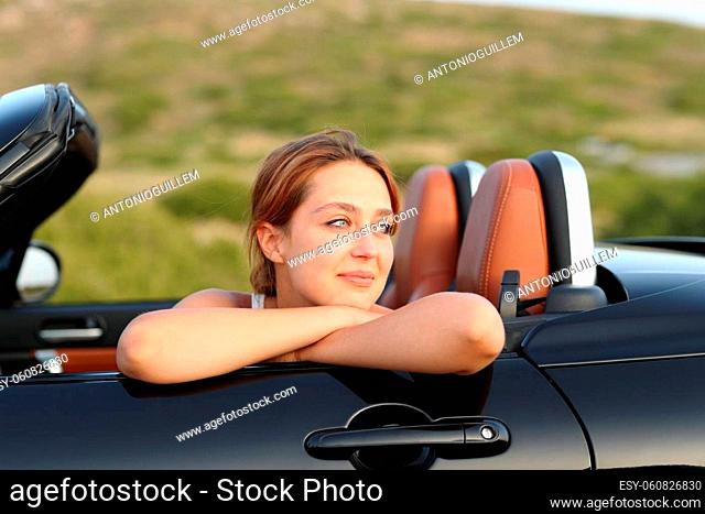 Satisfied owner looking away in a cabriolet car in the mountain