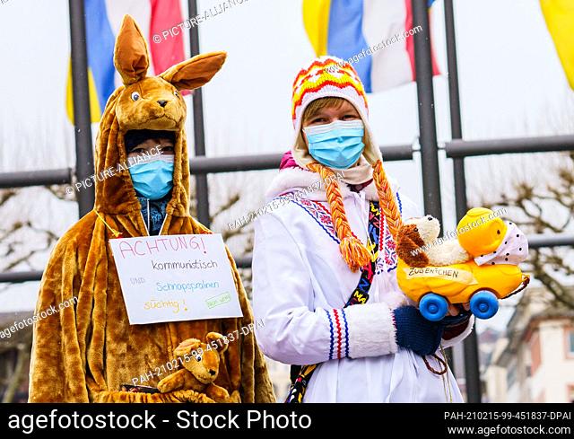 15 February 2021, Rhineland-Palatinate, Mainz: Antonia (l), dressed in a kangaroo costume, and Eva, dressed as an Inuit, stand in front of the carnival flags on...