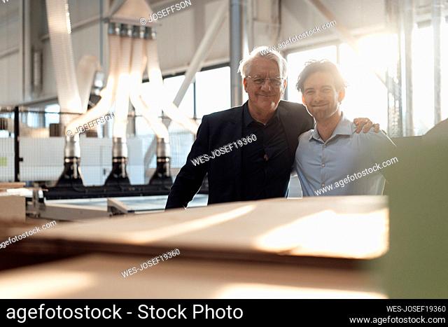 Smiling businessmen standing together in factory