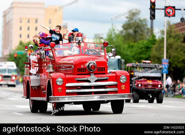 Louisville, Kentucky, USA - May 2, 2019: The Pegasus Parade, Man driving a antique firetruck during the parade, carrying children