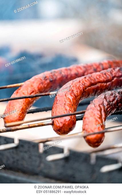 Brown and delicious pork and beef sausages being grilled on a home made turning grill