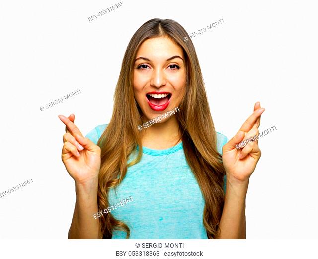 Indoor shot of glad happy young woman wears t-shirt smiles broadly, keeps fingers crossed, hopes for good luck, isolated against white background