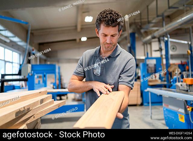 Portrait of carpenter examining plank of wood