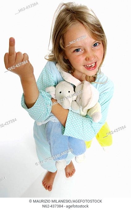 Angry little overhead view tightens the puppets in her arms and makes a rude gesture showing her middle finger raising arm