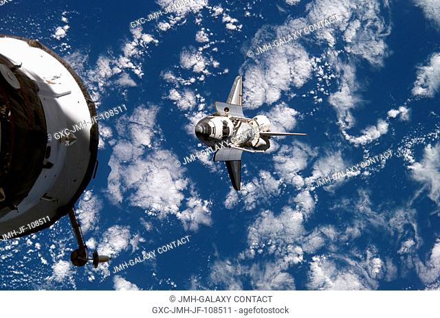 Backdropped by a blue and white Earth, Space Shuttle Discovery approaches the International Space Station during STS-120 rendezvous and docking operations