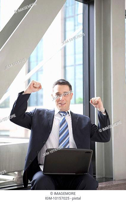 Business people sitting with laptop and raising fists with confidence