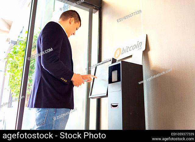 Bitcoin ATM machine being used by businessman for buying cryptocurrency and other altcoins