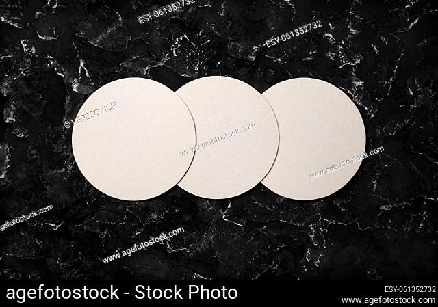 Three blank beer coasters on black plaster background. Responsive design mockup. Top view with copy space. Flat lay