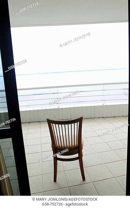 Empty chair in open doorway overlooking ocean