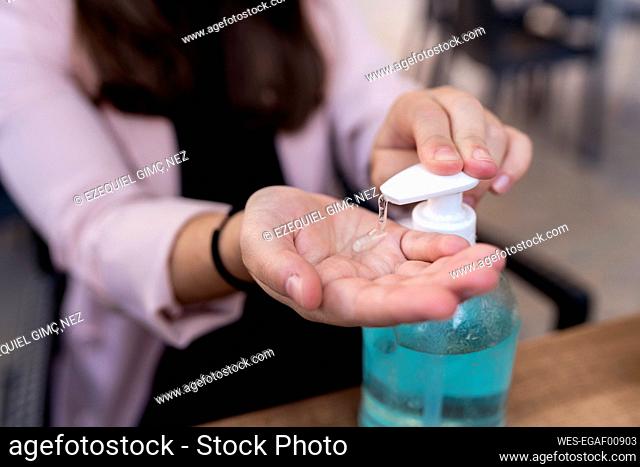 Businesswoman using hand sanitizer in cafe during coronavirus outbreak
