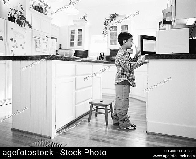 Young boy looking in microwave