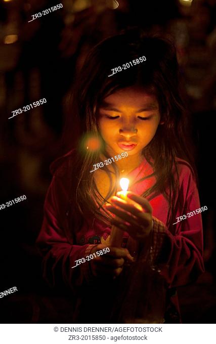 A young Cambodian girl prays at a small shrine next to the Mekong River in Phnom Penh, Cambodia