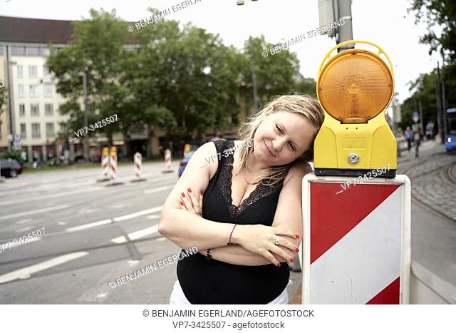 Woman beside signalling light on the street, Munich, Germany