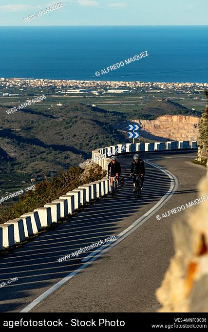 Sportsman and sportswoman cycling on mountain pass, Alicante, Spain