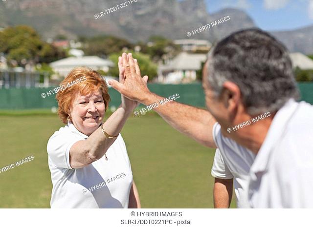 Older couple high fiving outdoors