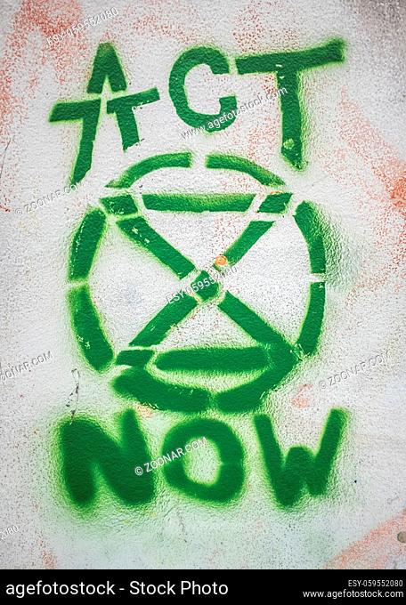 LONDON, UK ? JULY 16th 2019: Graffiti Of Extinction Rebellion Logo And 'Act Now' Slogan On A Wall During Protest Graffiti Of Extinction Rebellion Logo And 'Act...