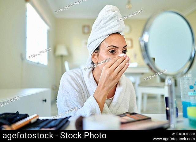 Woman removing make-up in living room