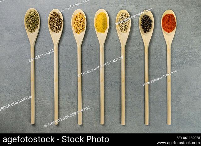 Various spices in wooden spoons side by side seen from above