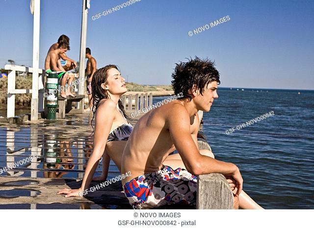 Young Couple Sitting on Edge of Pier