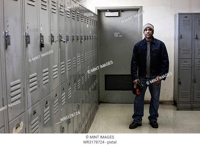 Black man factory worker standing next to lockers in a factory break room