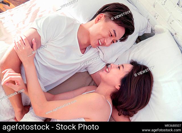 Sweet young lovers lying on the bed face to face