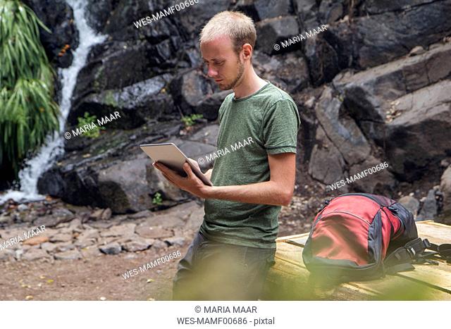 Hiker taking a break at rest area and using tablet, Barranco el Cedro, La Gomera, Canary Islands, Spain