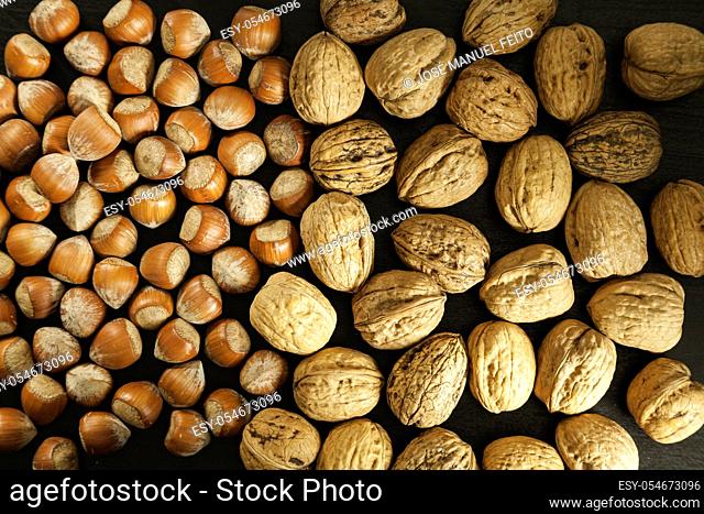 Hazelnuts and walnuts half and half on dark background top view