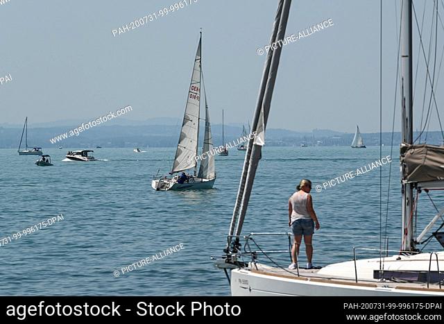 31 July 2020, Baden-Wuerttemberg, Gohren Am Bodensee: Several sailing boats sail off Gohren on Lake Constance. More than 32 degrees Celsium is indicated by the...