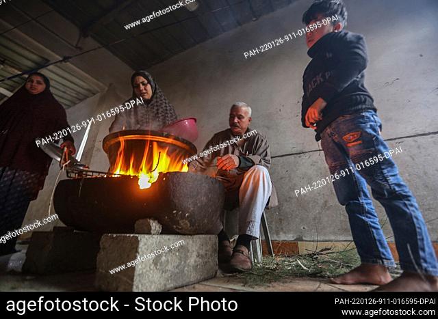 26 January 2022, Palestinian Territories, Beit Lahia: A Palestinian family burns a fire for heating and cooking indoors during the cold weather of the winter...